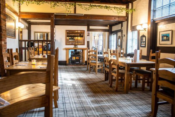 Dining room with fireplace and wooden tables at The Horse and Jockey Bentley