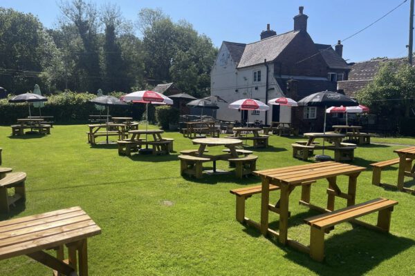 Beer garden with picnic tables and pub exterior at The Horse and Jockey Bentley
